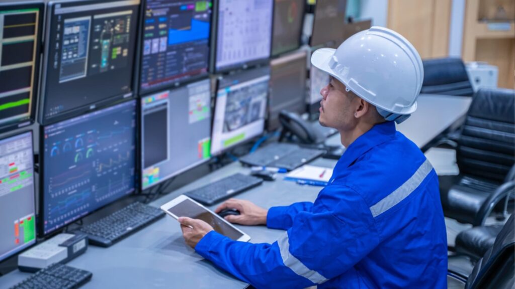 Warehouse technician monitoring refrigeration and temperature control systems through digital control panels and real-time data dashboards.